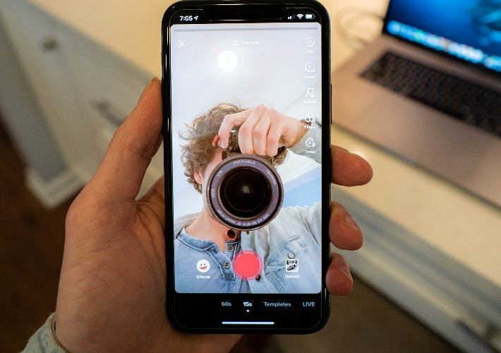 man holding camera in phone screen
