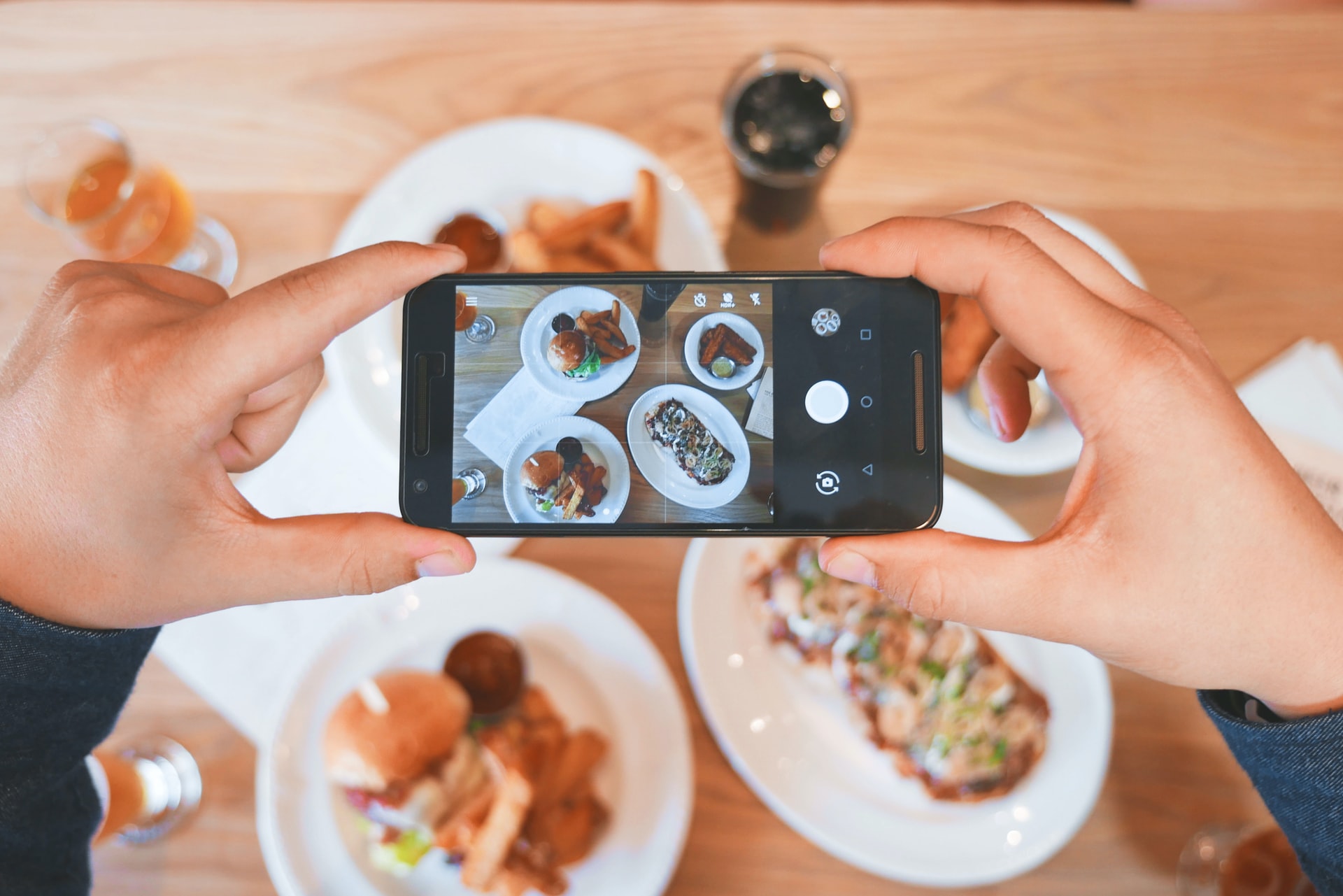 Persona tomando foto de distintos platillos con el celular para crear reels de Instagram