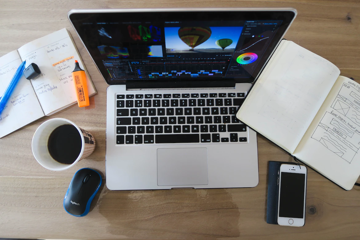 Laptop and stationery with a cup of coffee on top of a wooden table